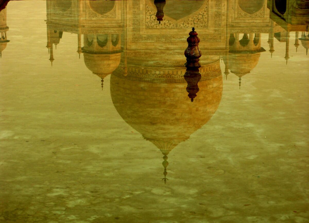 Stunning reflection of the Taj Mahal's dome in tranquil water, showcasing architectural grandeur.