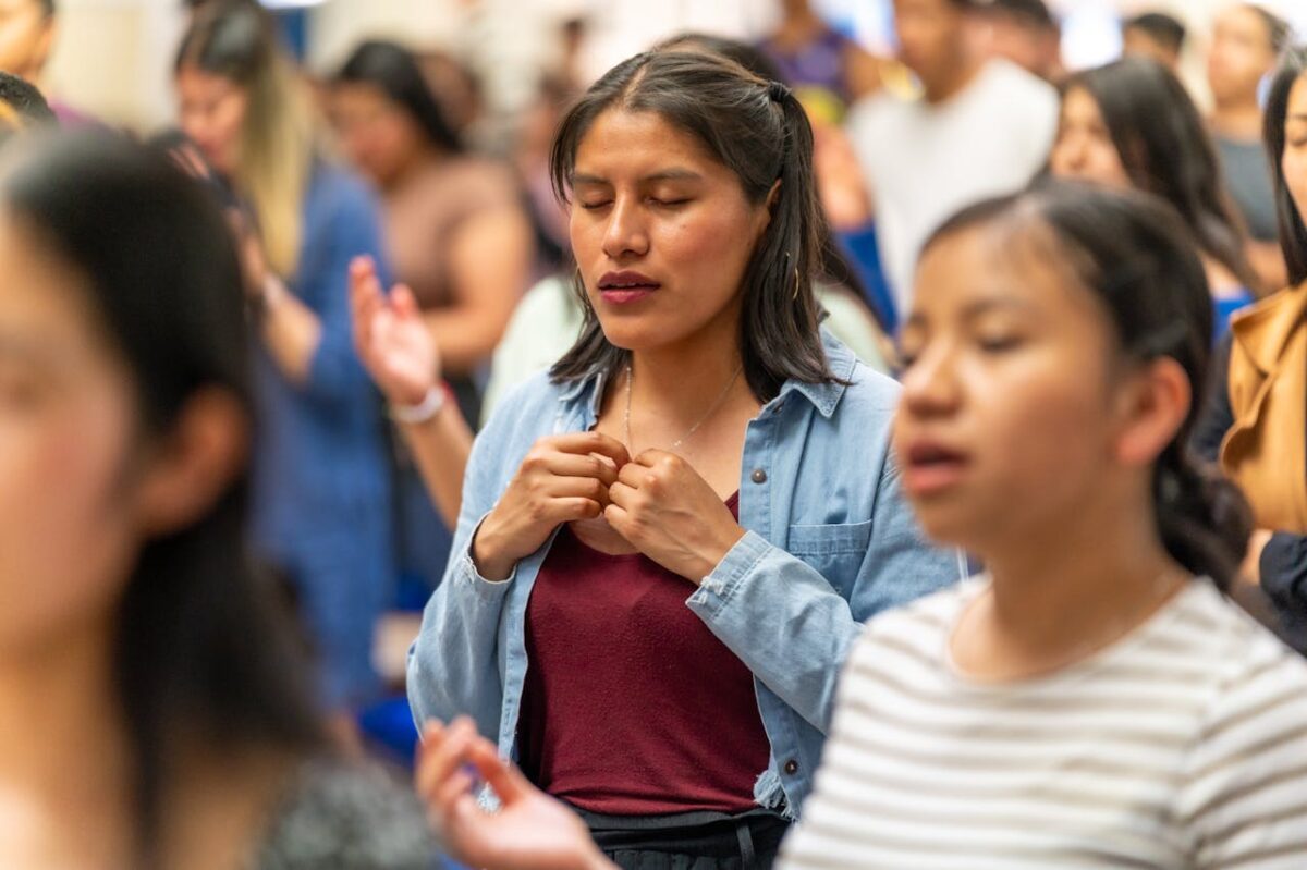 Young woman deeply praying in a church congregation in Ciudad de México, México.