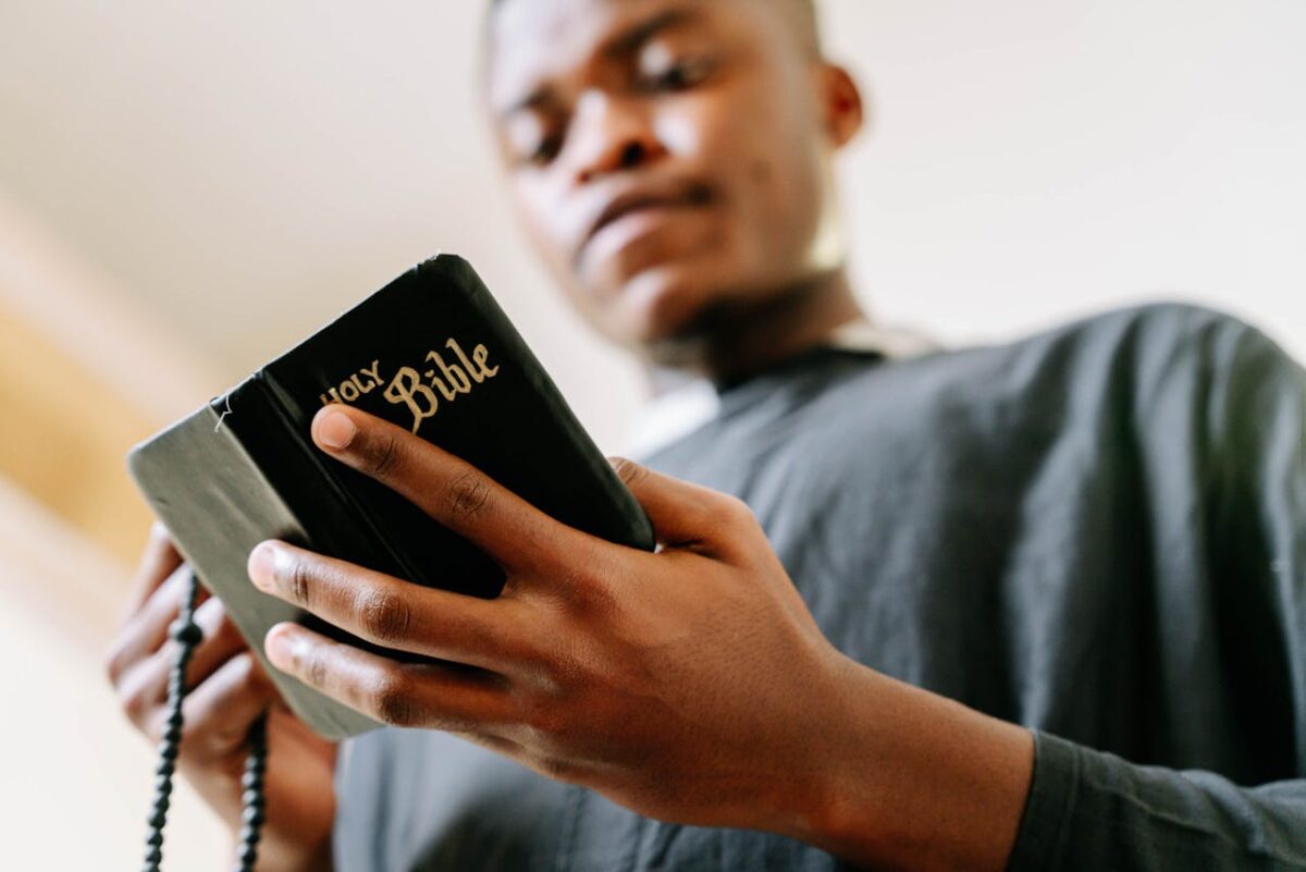 A young man holds and reads the Bible, symbolizing faith and devotion in an intimate setting.